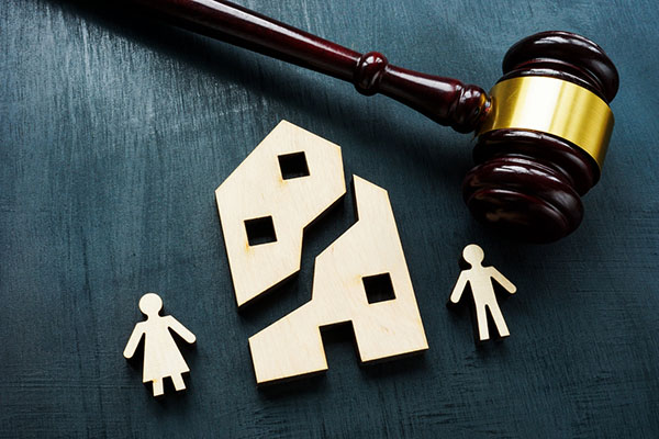 Dividing a house during divorce with gavel and split home model representing legal property separation
